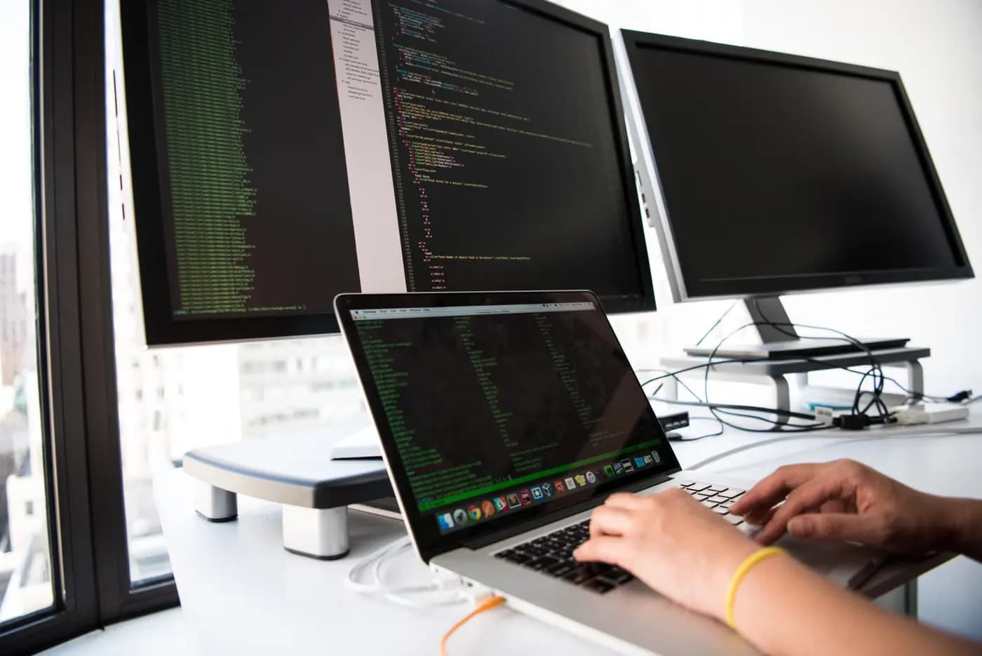 A developer working across laptop and monitor